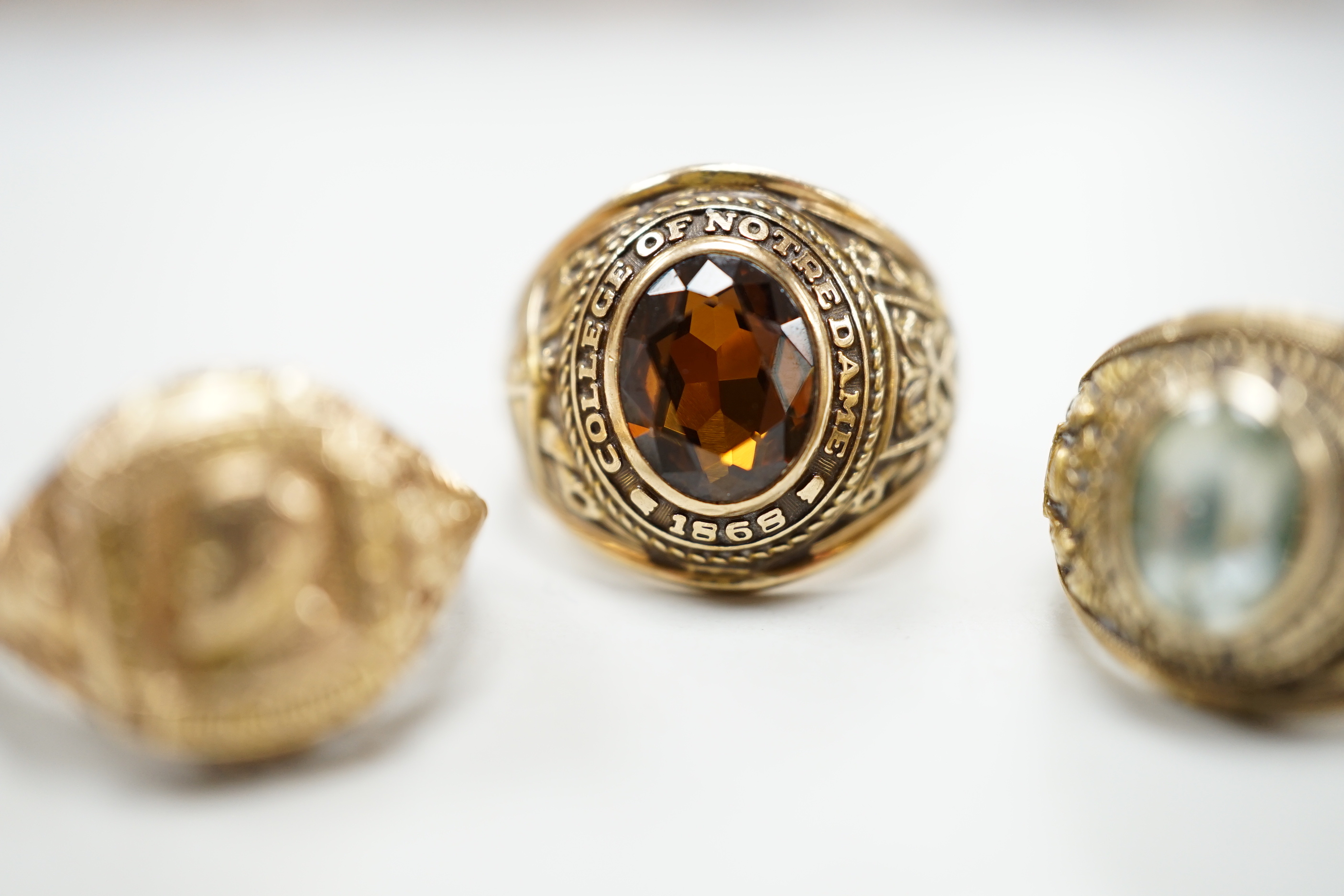 Three assorted American 10k dress rings, two set with gems, one signed John Roberts, gross weight 18.9 grams.